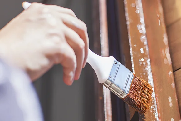 Hand streicht Holz braun